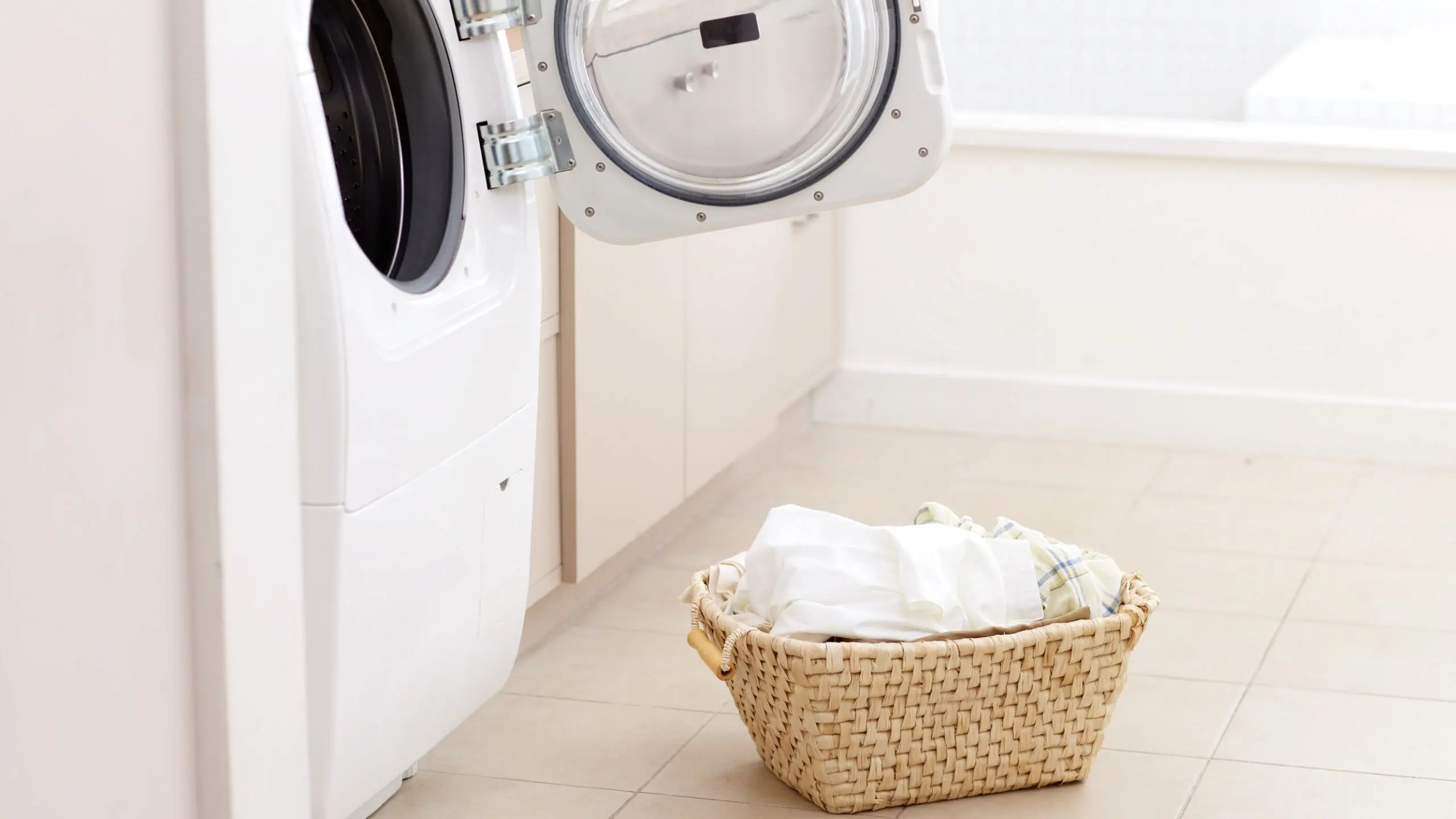 Best laundry service in Doha with a modern washing machine and neatly arranged laundry basket