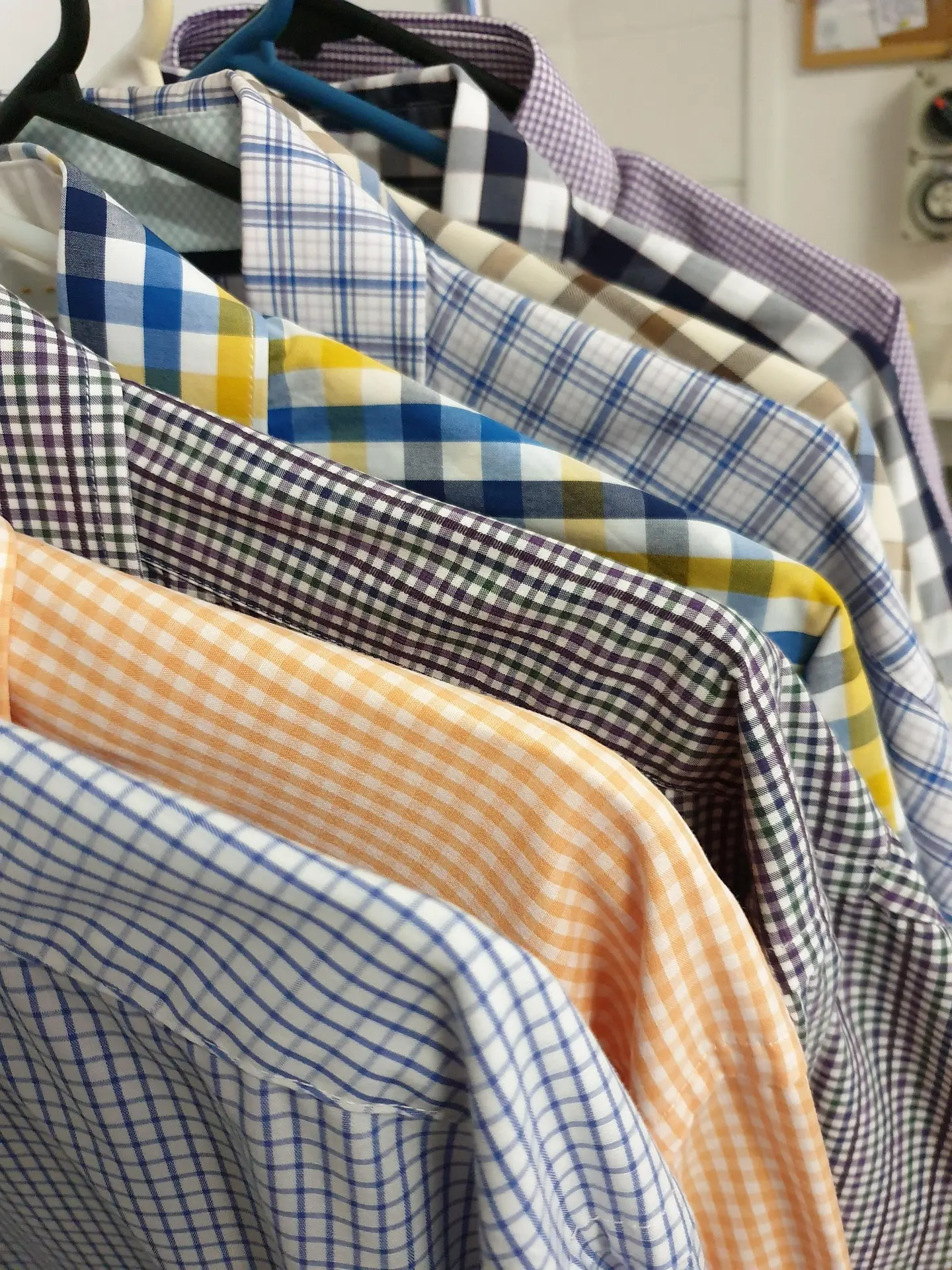  freshly cleaned shirts hanging neatly on hangers at a professional laundry service in Doha